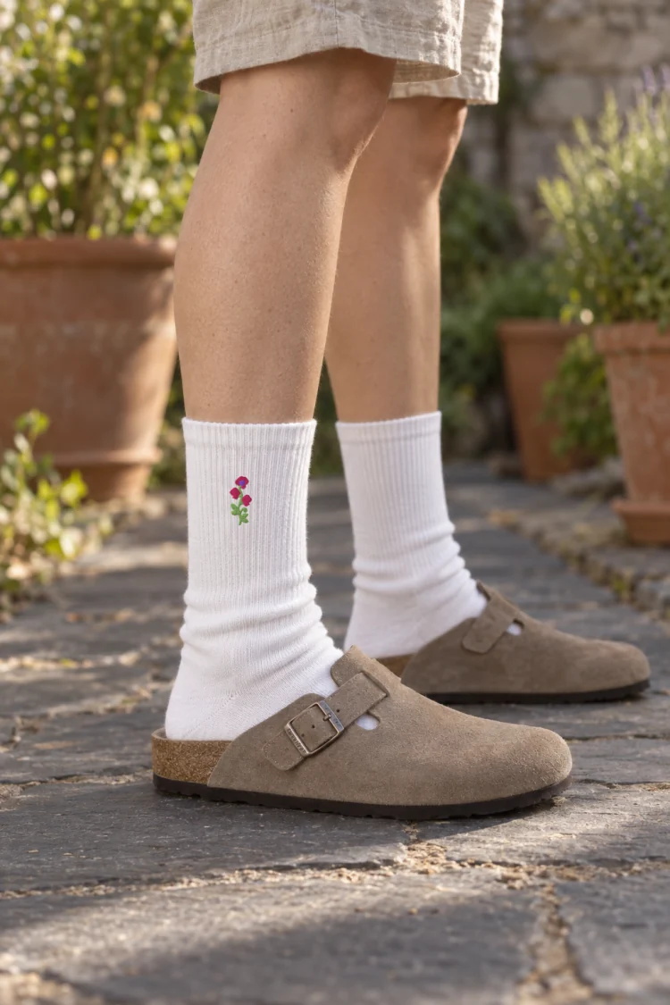 AI-generated image of the April Sweet Pea Birth Flower Socks in White, worn with a sunny cottage garden path of dark slate.