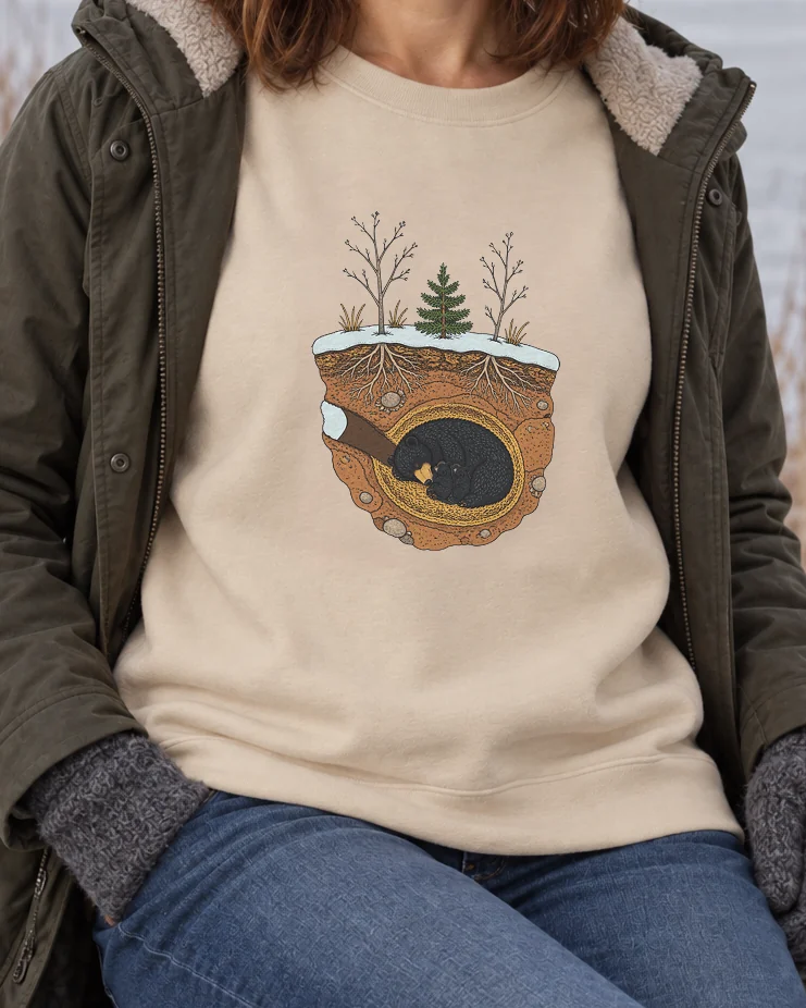 AI-generated image of a fictional model wearing the Black Bear in Winter Crewneck in Sand, size M, at 5′4″ tall, cropped to the print.